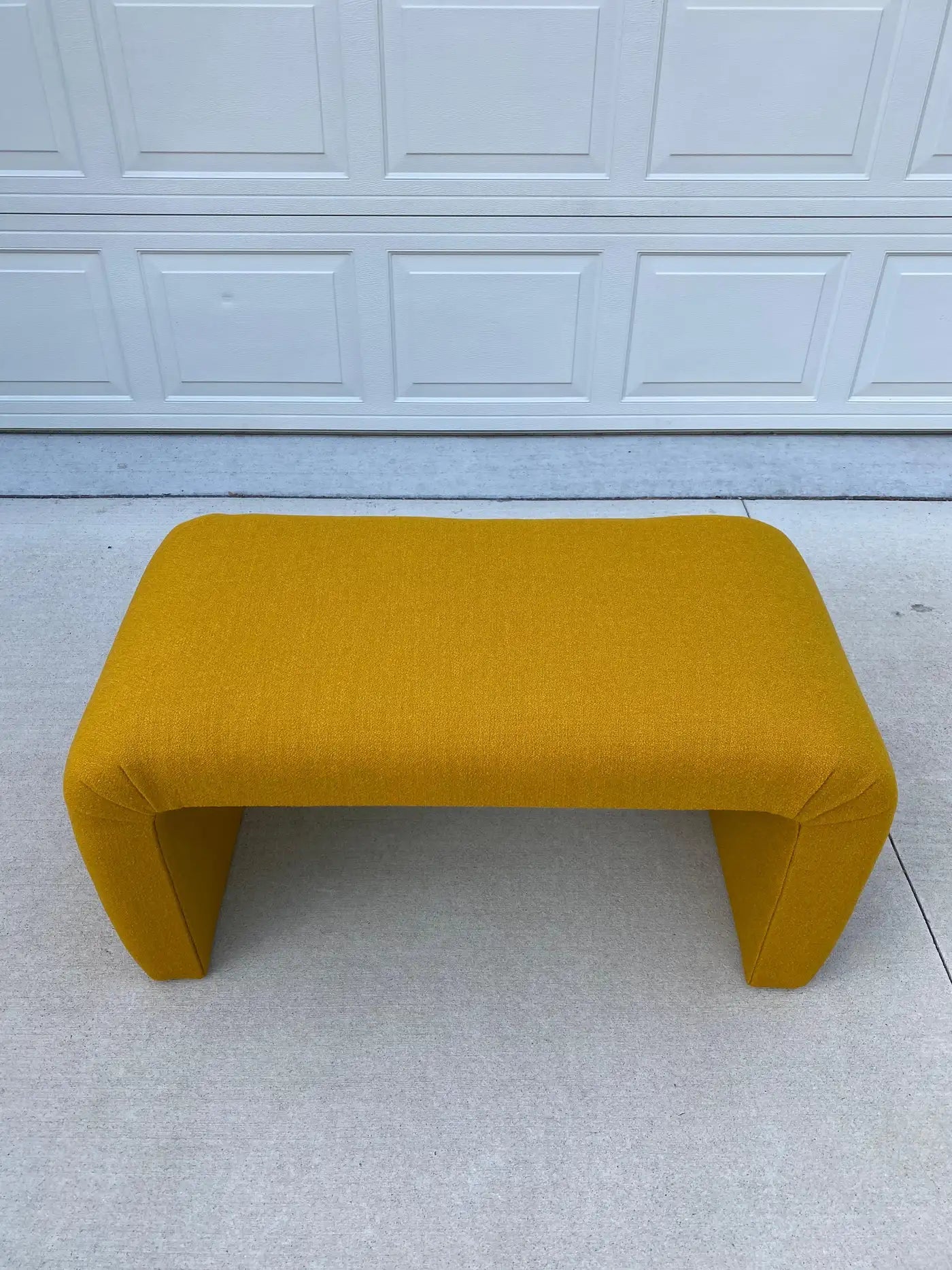 Yellow bench on a light gray floor with a white paneled wall in the background