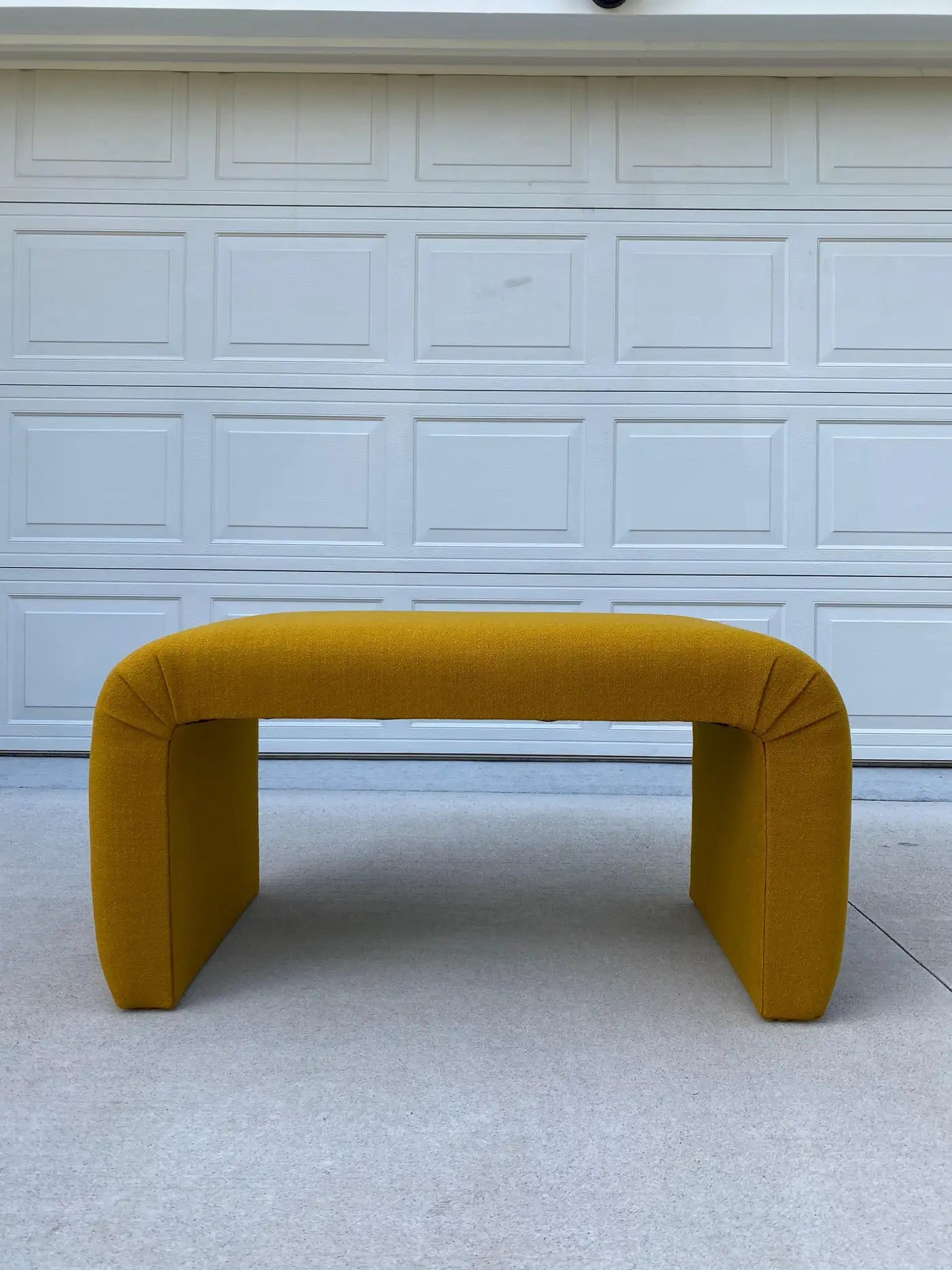 Mustard yellow bench in front of a white garage door