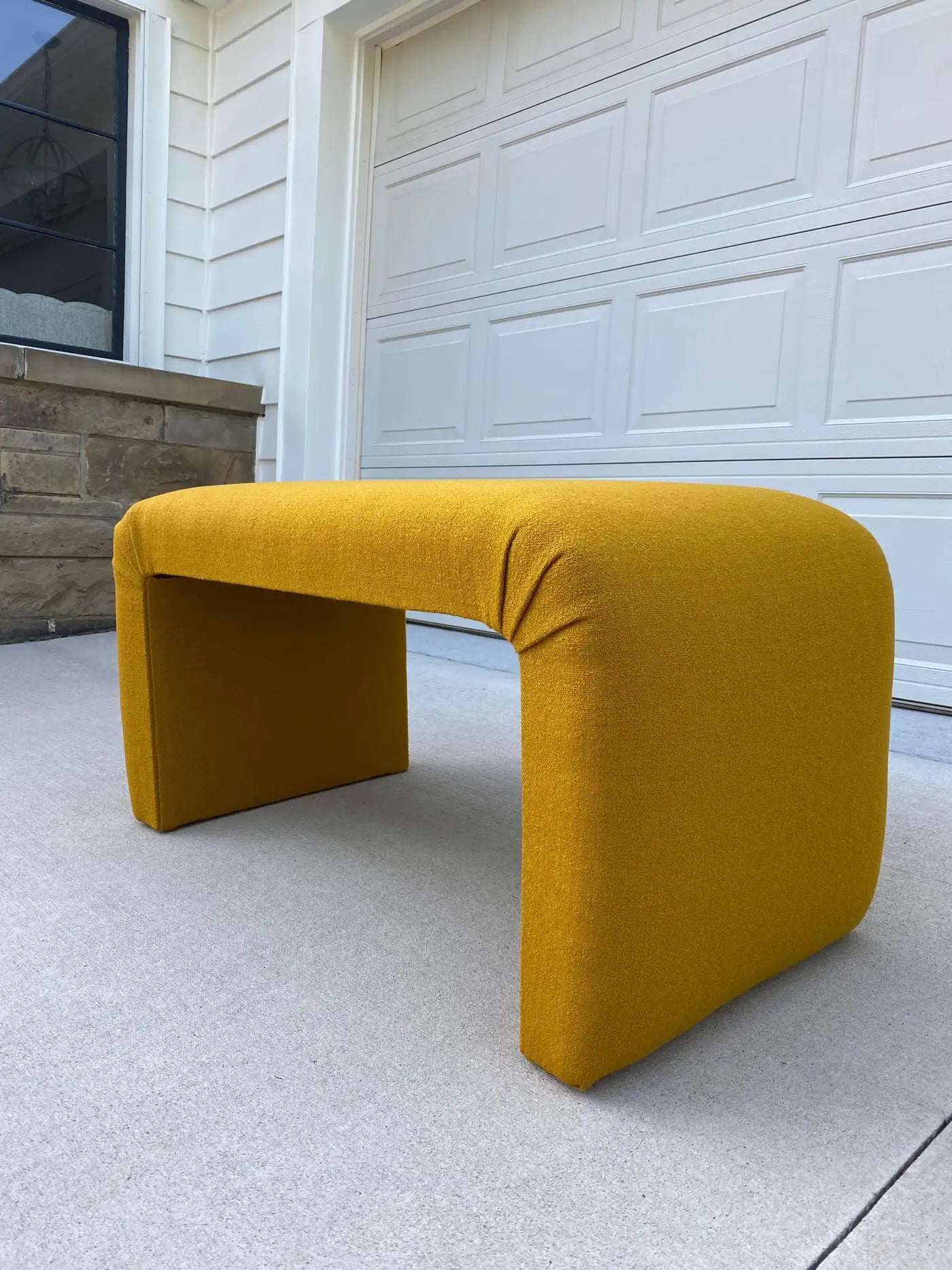 Yellow bench on a concrete surface with a garage door in the background