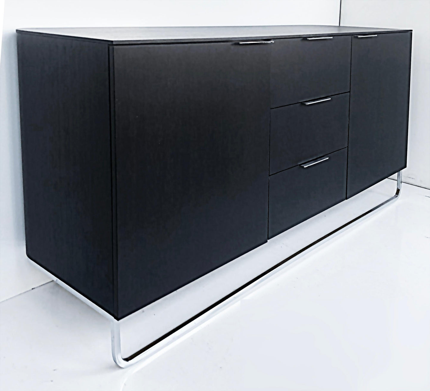 Black sideboard with drawers on a white floor and wall