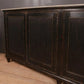 Dark wooden sideboard with three doors against a gray wall.