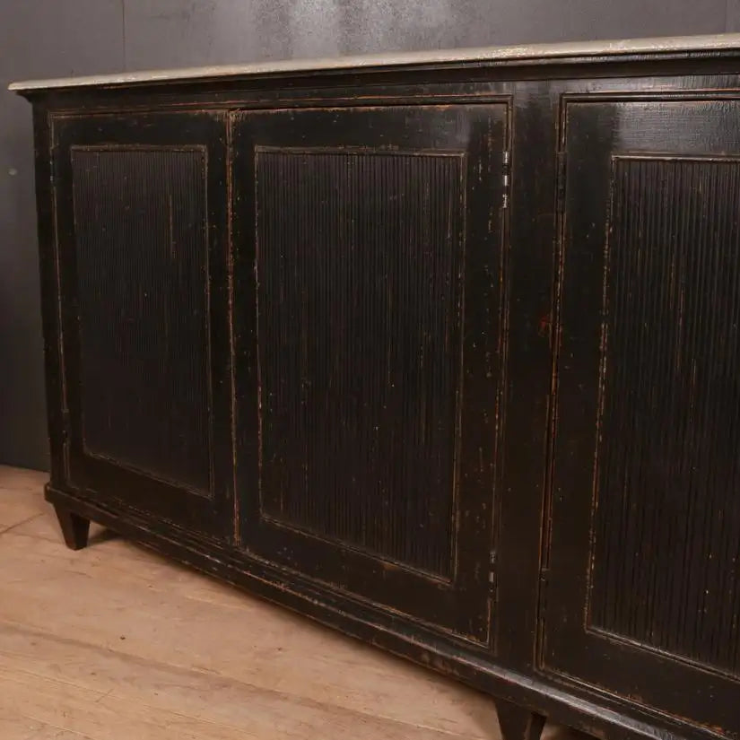 Dark wooden sideboard with three doors against a gray wall.