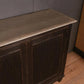 Vintage wooden cabinet with a metal top against a gray wall.