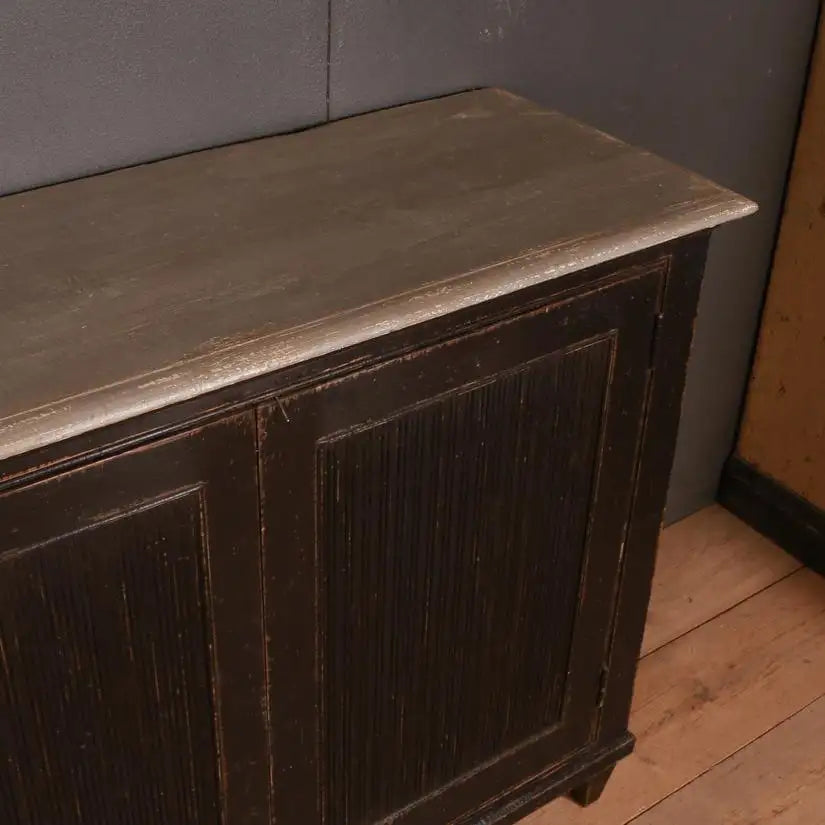 Vintage wooden cabinet with a metal top against a gray wall.