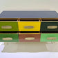 Colorful dresser with six drawers in green, yellow, and brown on a white background