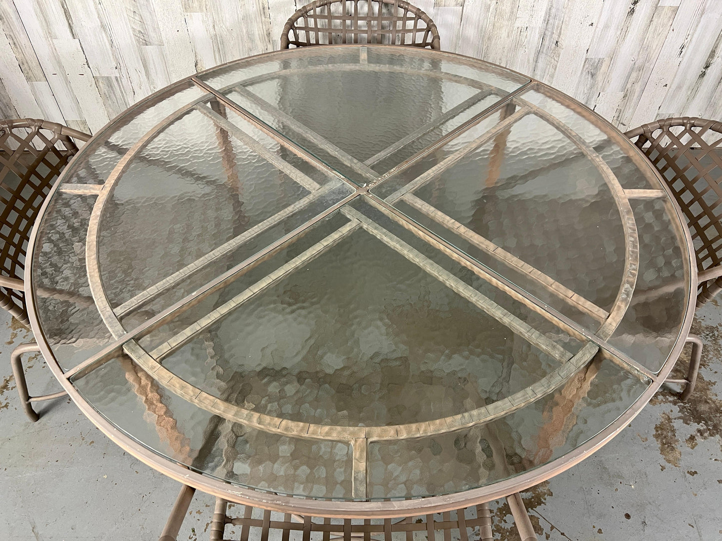Round glass dining table with metal frame on a concrete floor