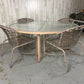 Outdoor patio set with a glass-top table and wicker chairs in an indoor setting.