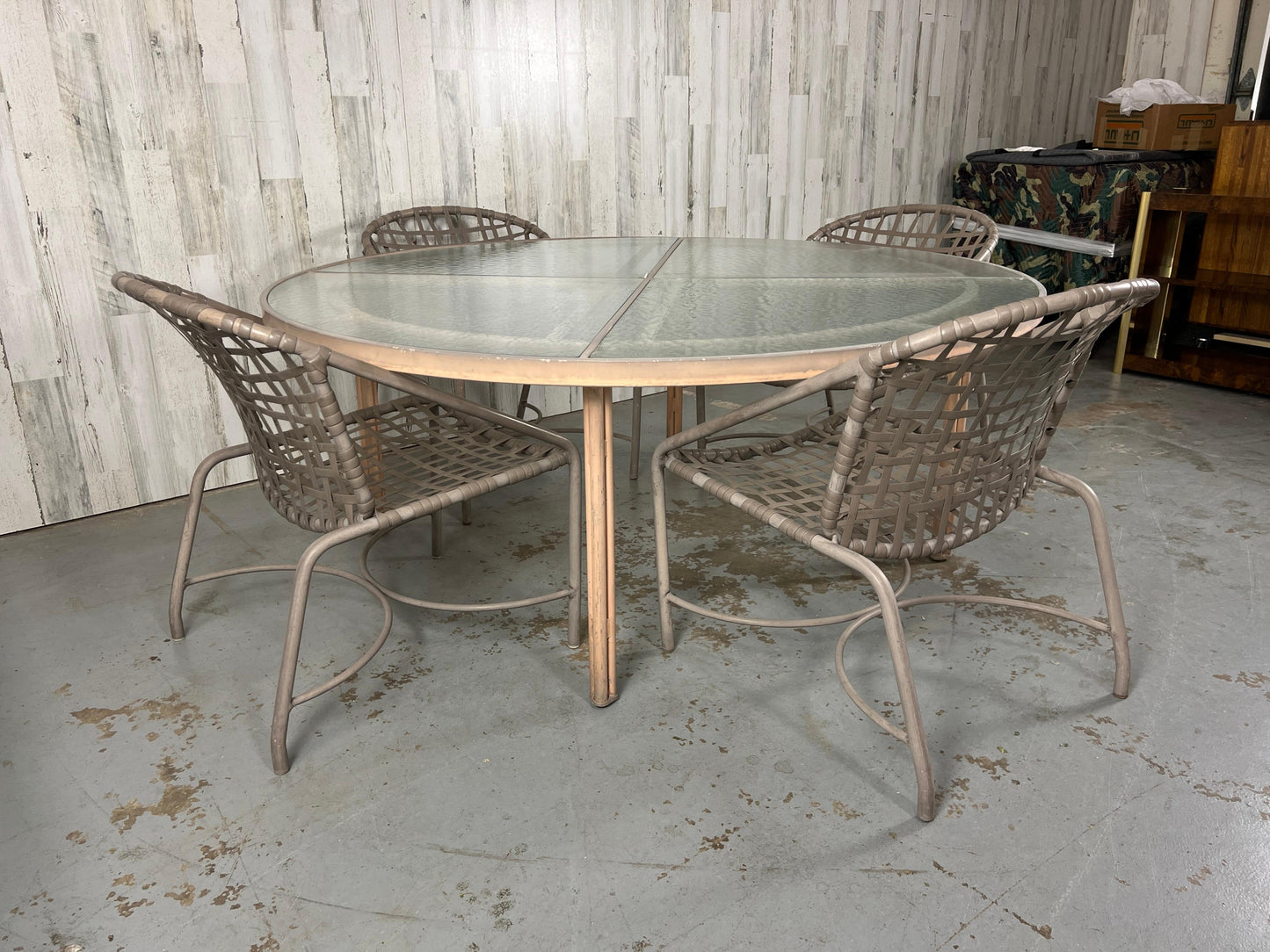 Outdoor patio set with a glass-top table and wicker chairs in an indoor setting.
