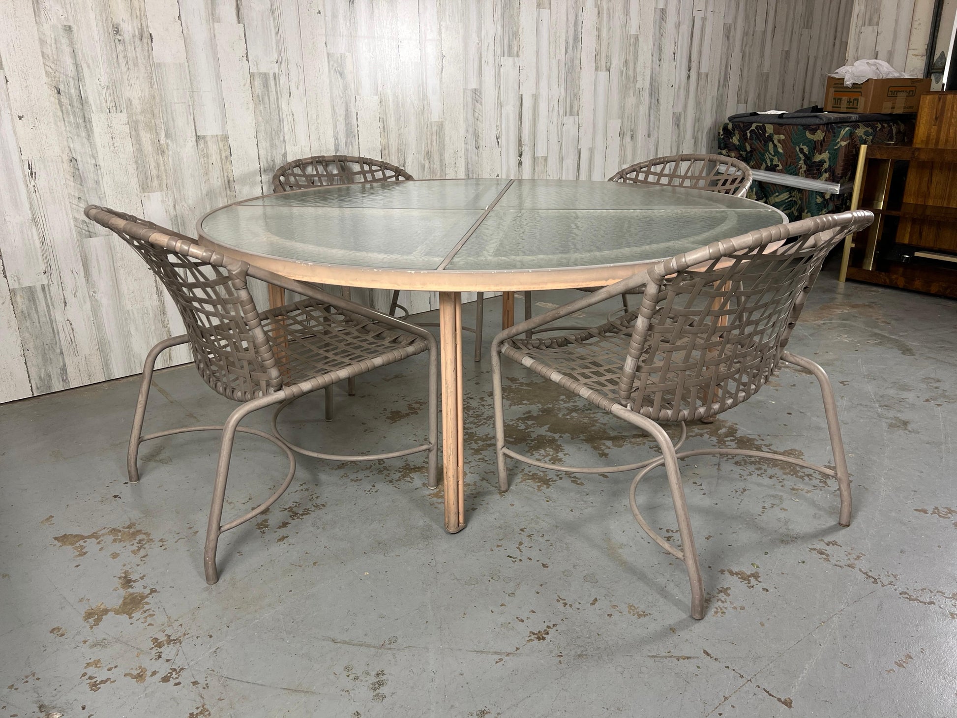 Outdoor patio set with a glass-top table and wicker chairs in an indoor setting.