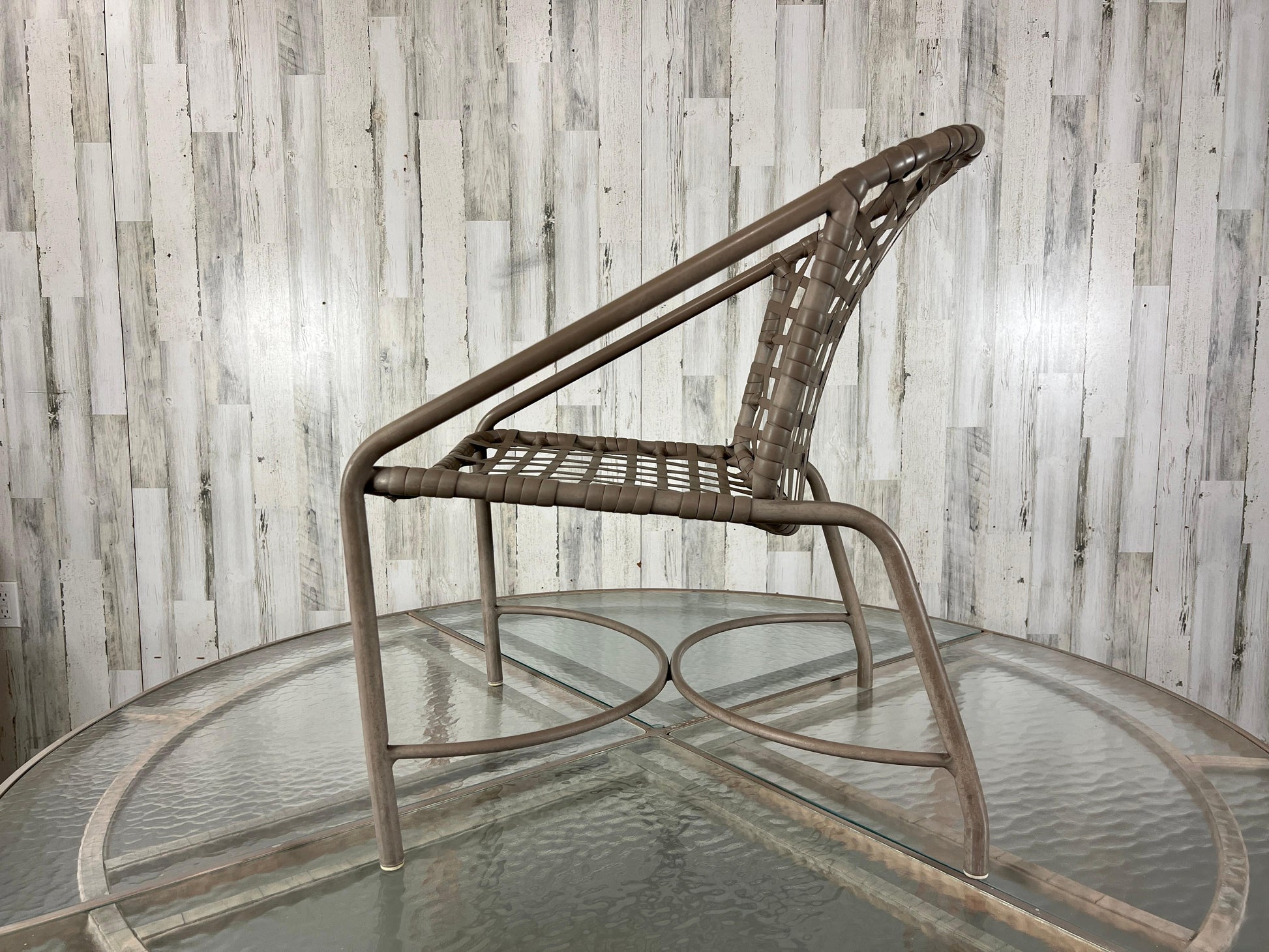 Wicker chair on a glass table against a wooden paneled wall