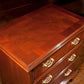 Wooden desk with leather top and gold handles on a wooden floor