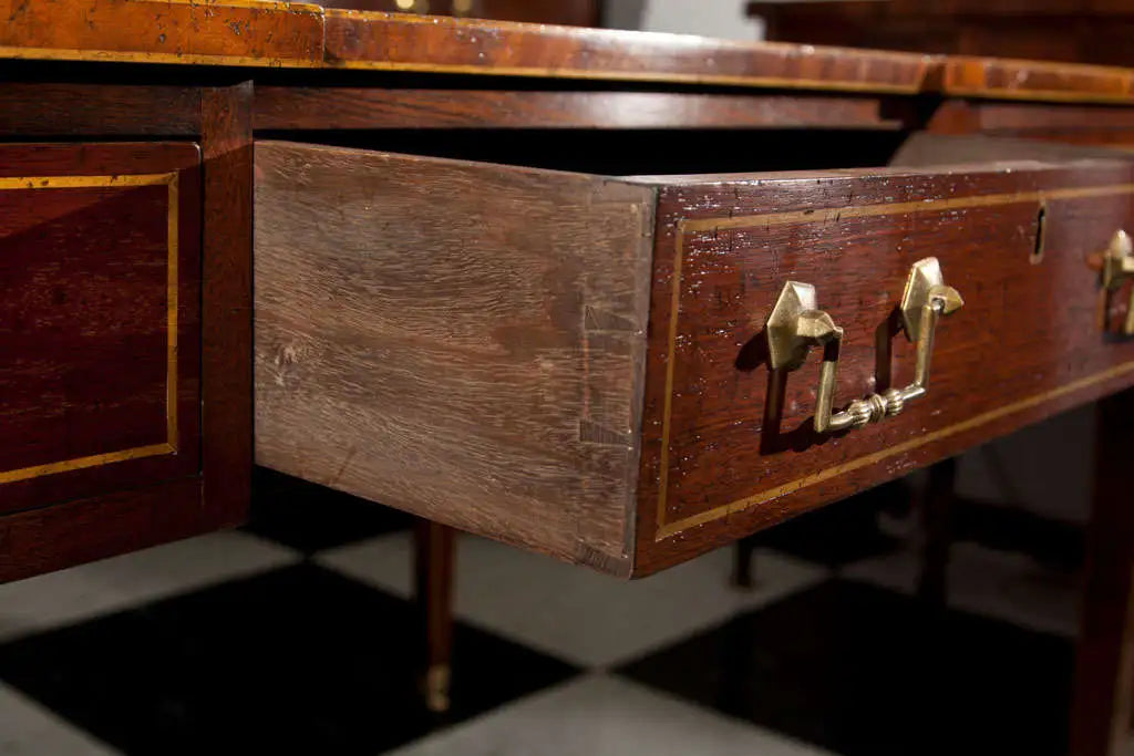 Wooden drawer with brass handles on a checkered floor