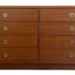 Wooden dresser with multiple drawers and brass knobs on a white background