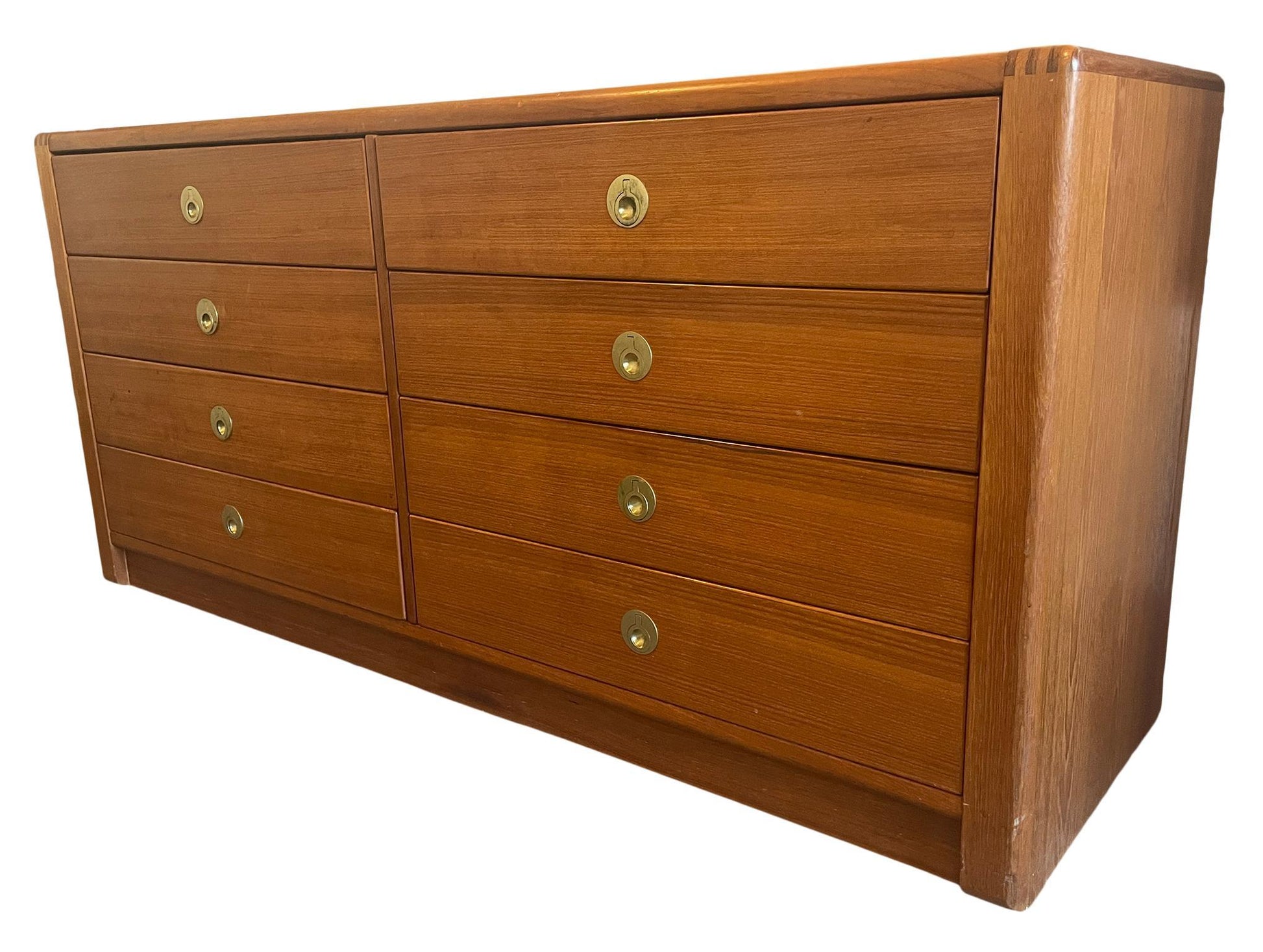 Wooden dresser with multiple drawers and brass handles on a white background