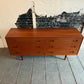 Wooden dresser against a textured wall with peeling paint