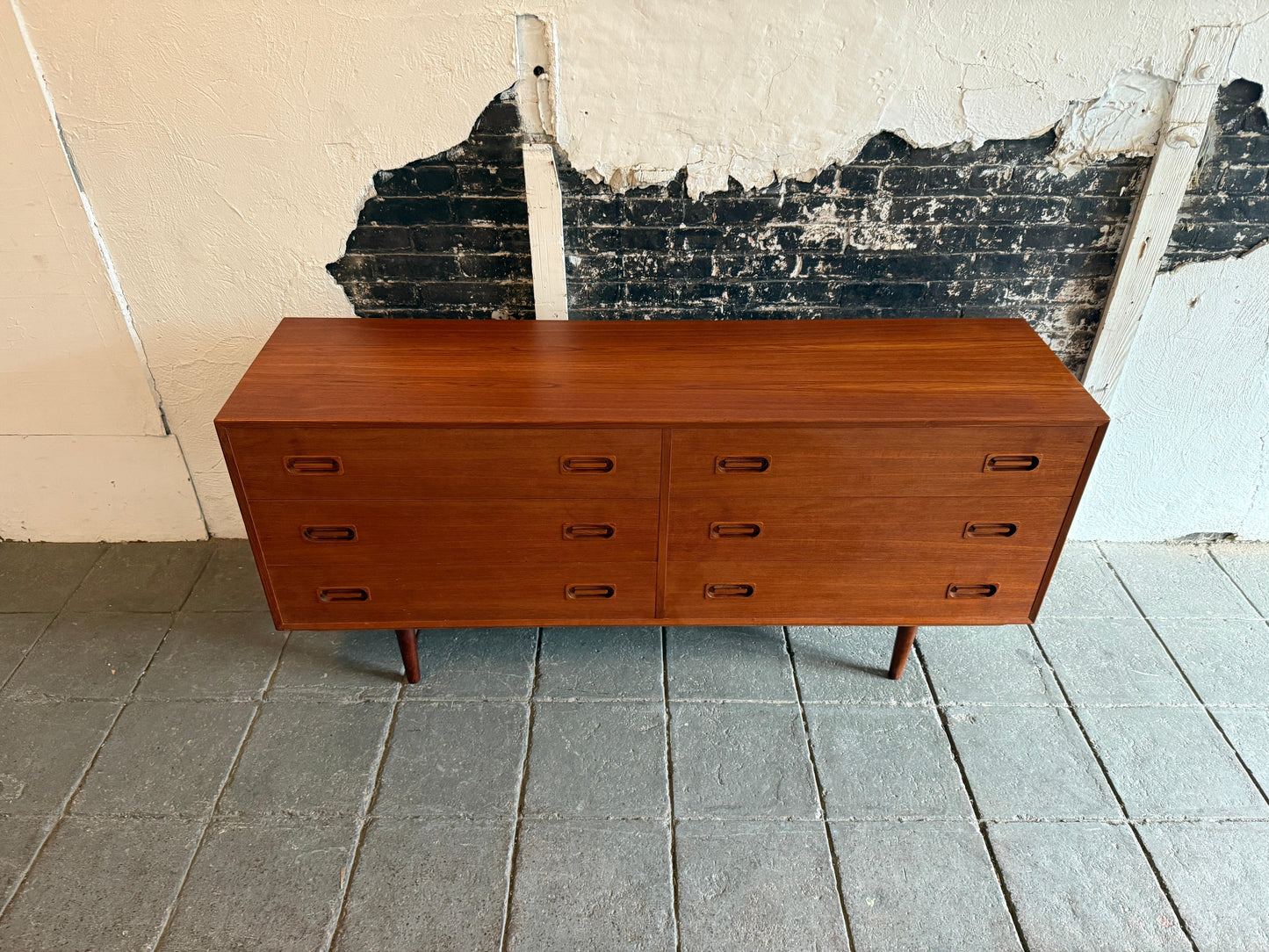 Wooden dresser against a textured wall with peeling paint