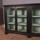 Vintage glass-fronted cabinet with dark wood frame on a wooden floor.