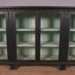 Vintage wooden cabinet with glass doors on a wooden floor.