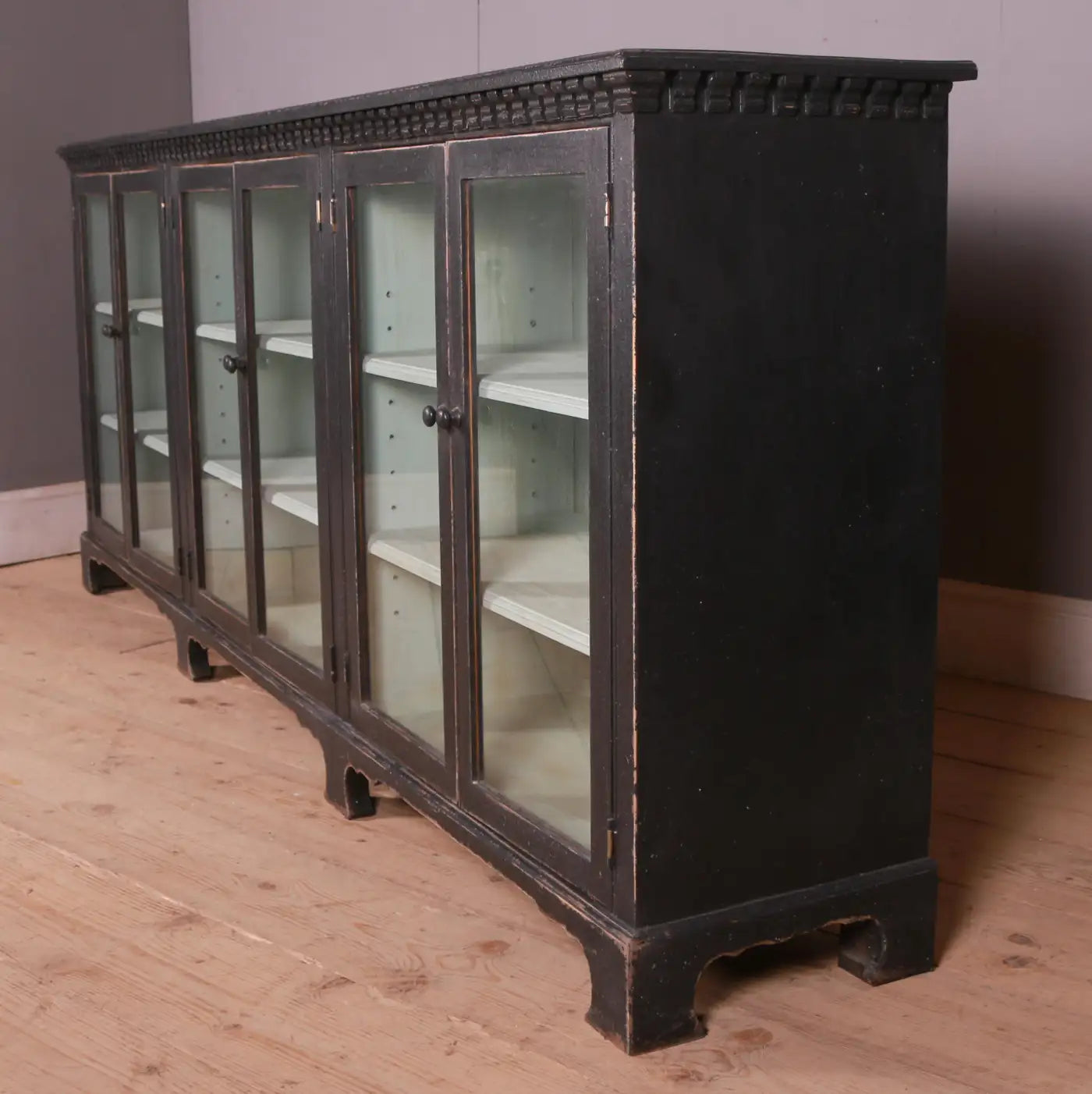 Vintage black cabinet with glass doors on a wooden floor.