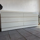 White dresser against a white wall on a tiled floor