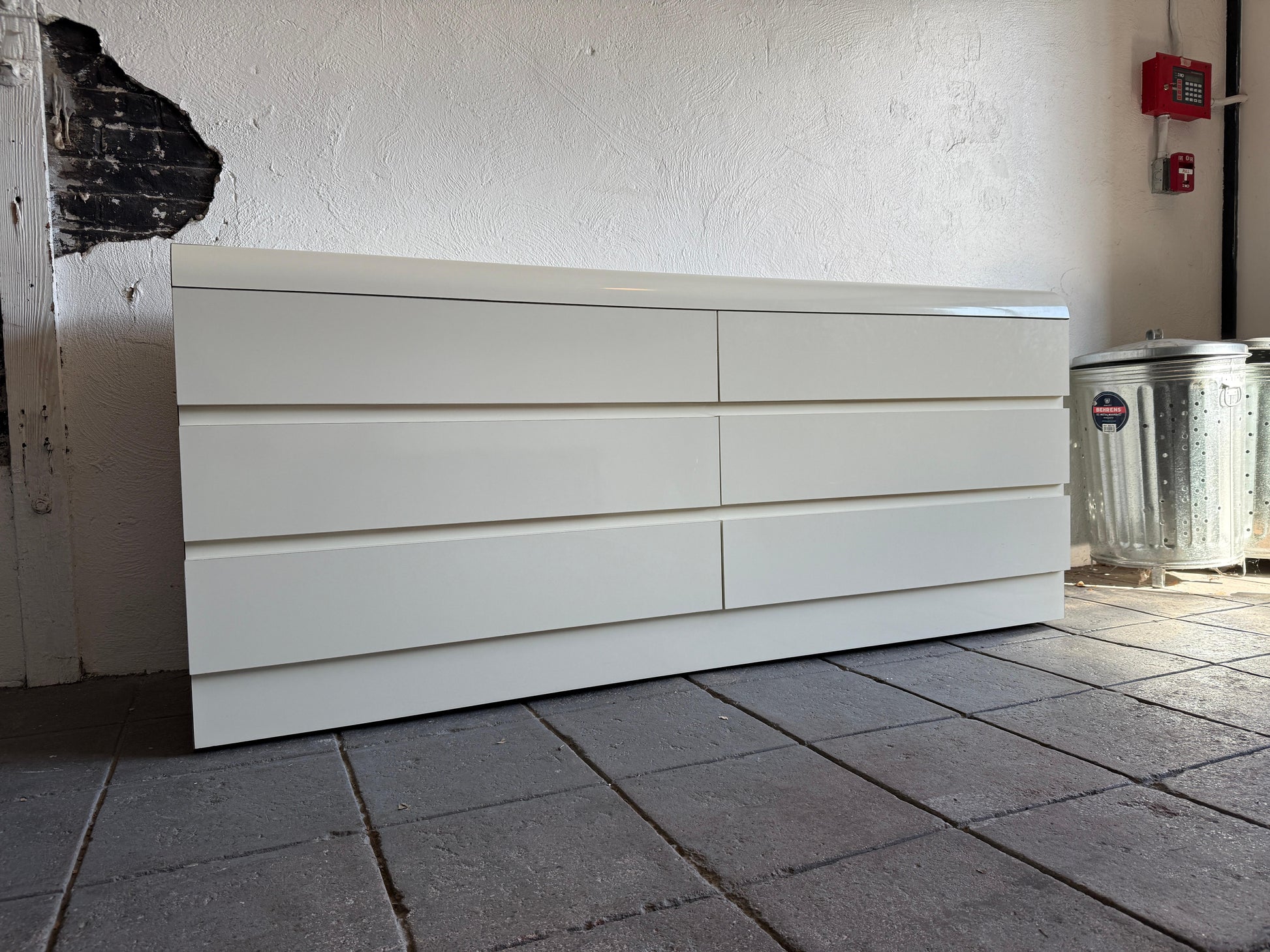 White dresser against a white wall on a tiled floor