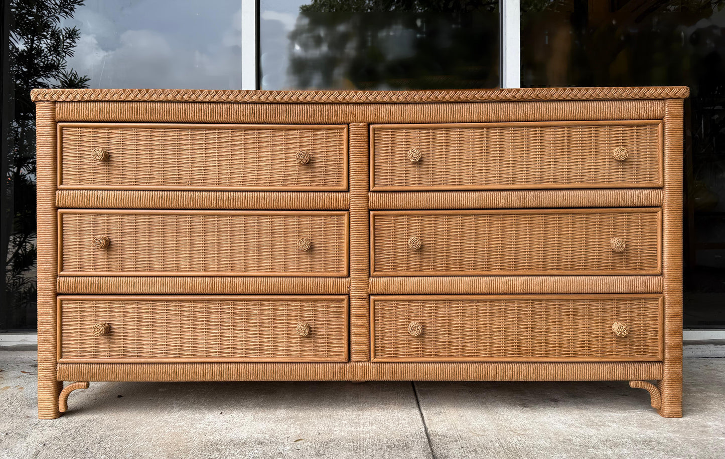 Wicker dresser with six drawers on a concrete surface.