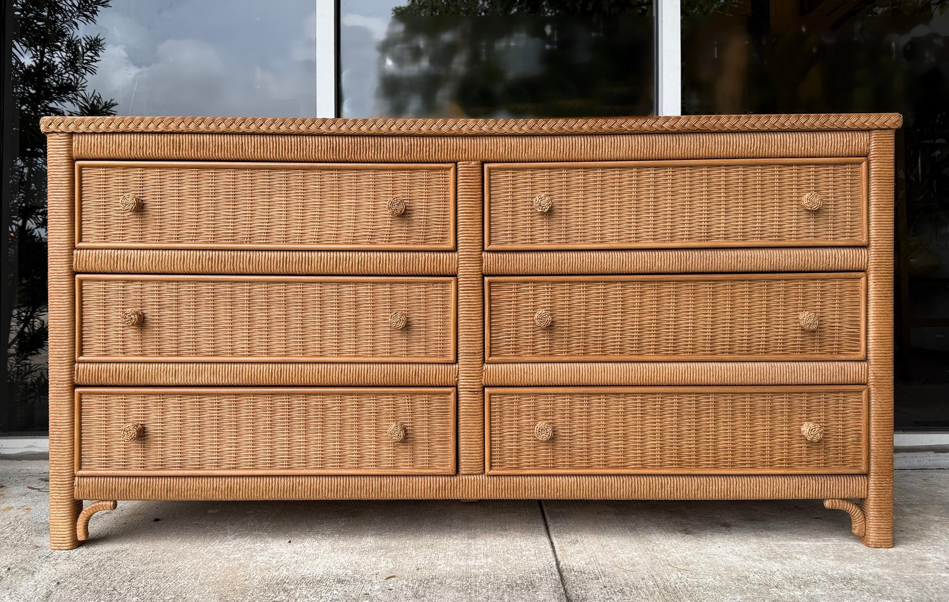 Wicker dresser with six drawers on a concrete surface.