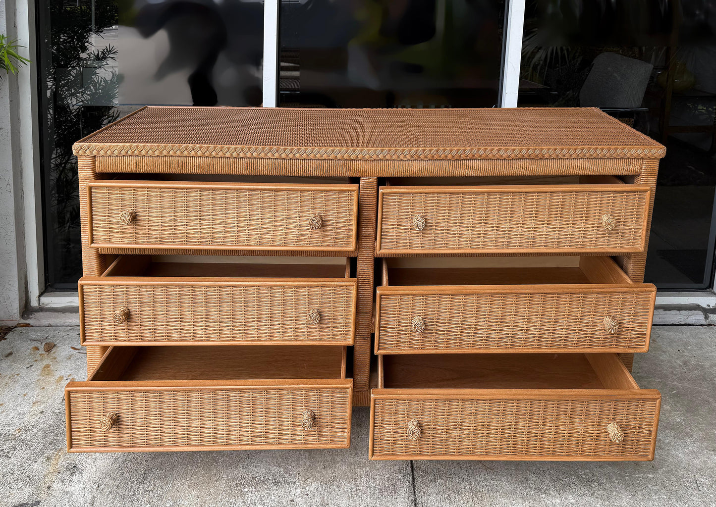 Wicker dresser with multiple drawers on a concrete surface