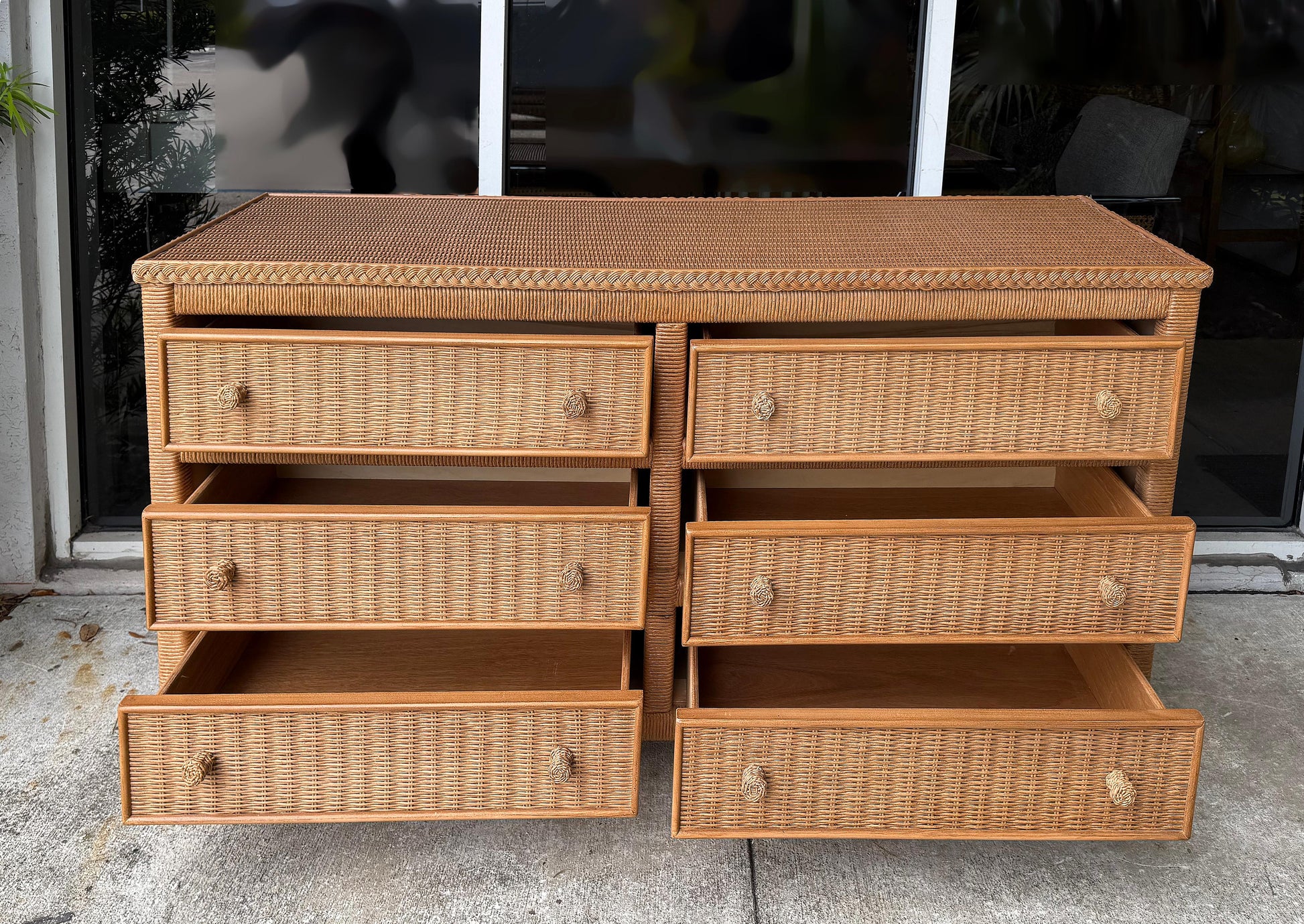 Wicker dresser with multiple drawers on a concrete surface