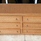 Wicker dresser with multiple drawers on a concrete floor.