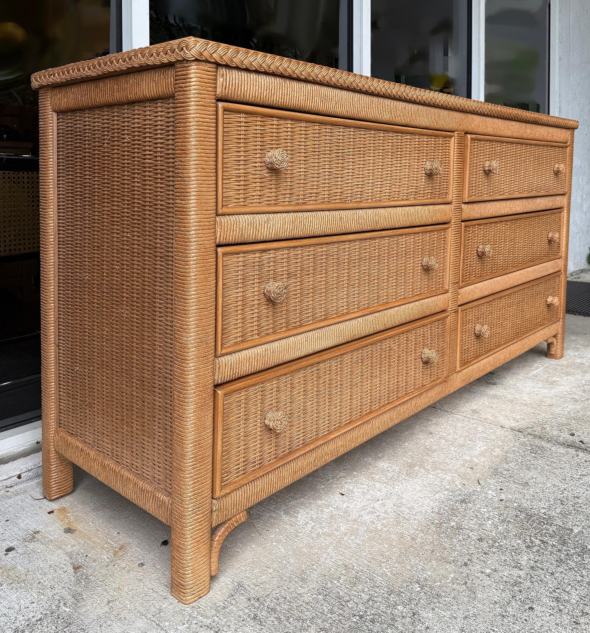 Wicker dresser with multiple drawers on a concrete surface