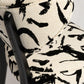 Chair with black abstract pattern on beige fabric against a light gray background