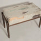 Small ottoman with patterned cushion on a plain background