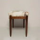 Wooden stool with patterned cushion on a plain background