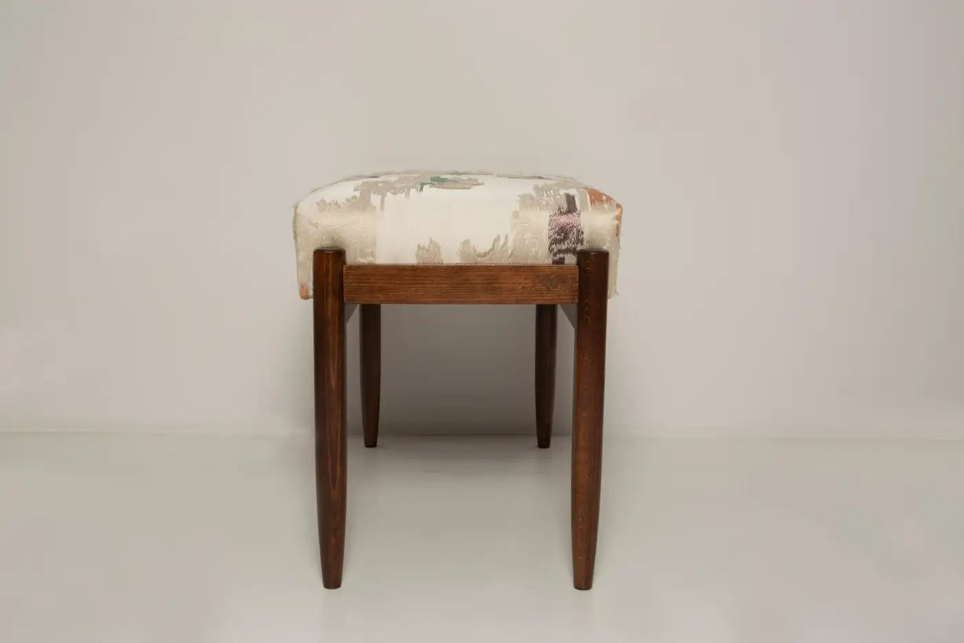 Wooden stool with patterned cushion on a plain background