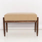 Beige cushioned bench with wooden frame on a white background