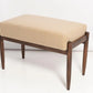 Beige cushioned bench with wooden legs on a white background