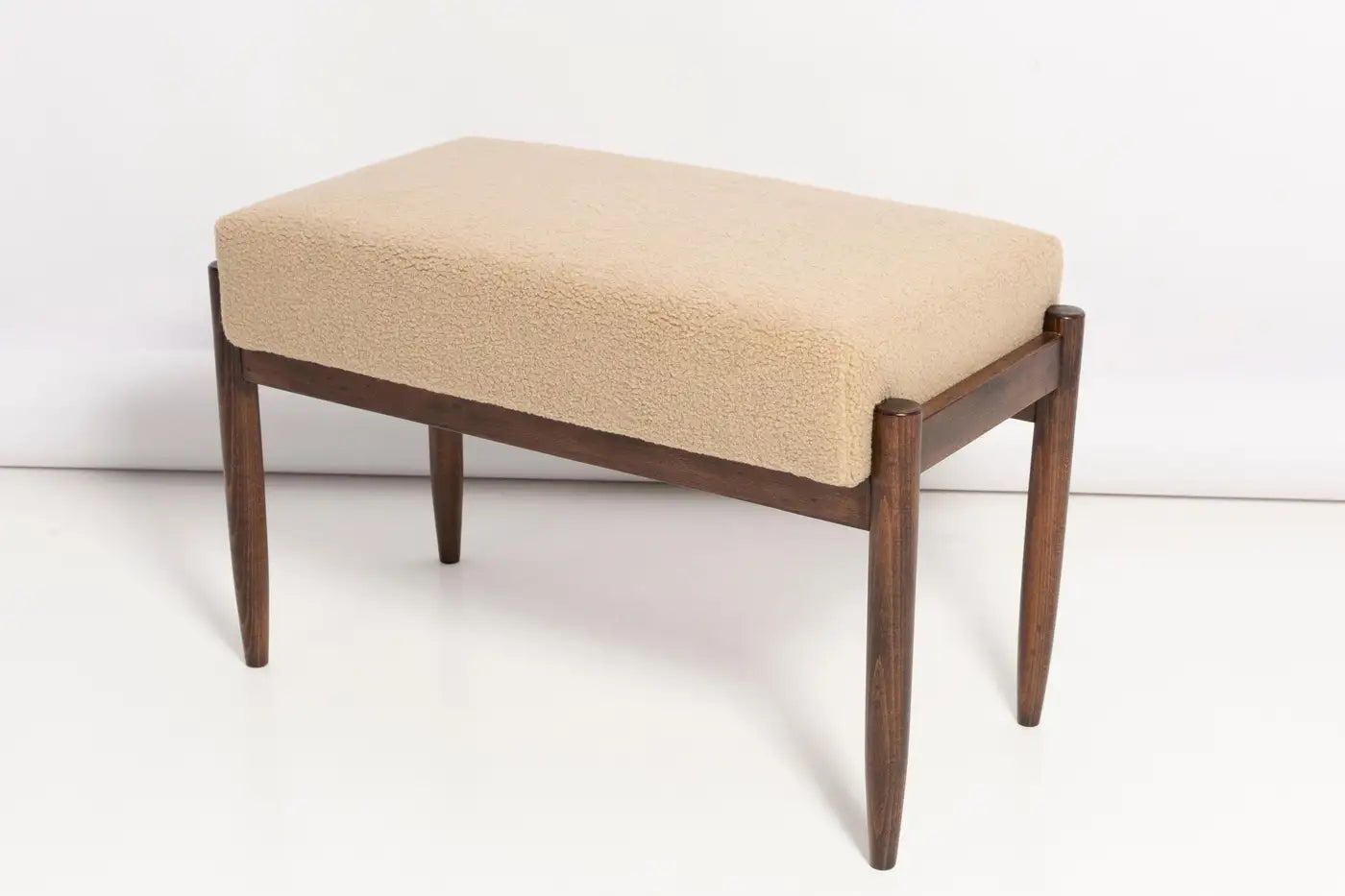 Beige cushioned bench with wooden legs on a white background