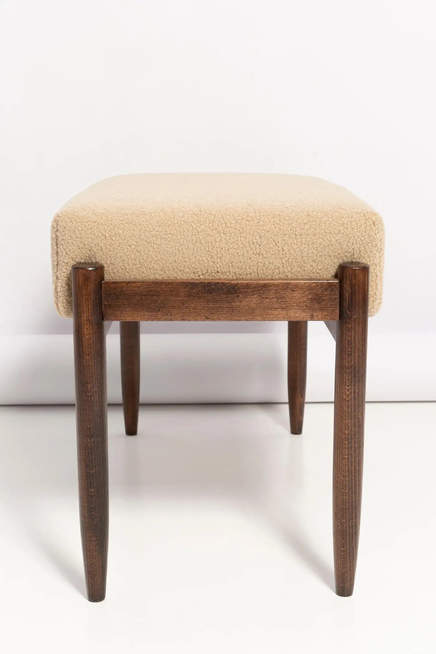 Wooden stool with beige cushioned seat on a white background