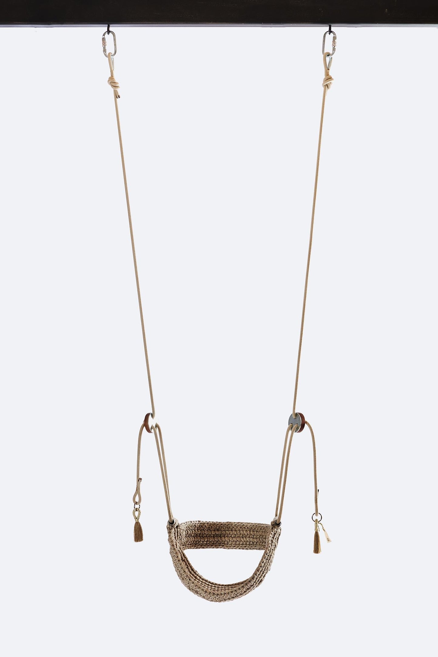 Brown woven swing hanging against a white background