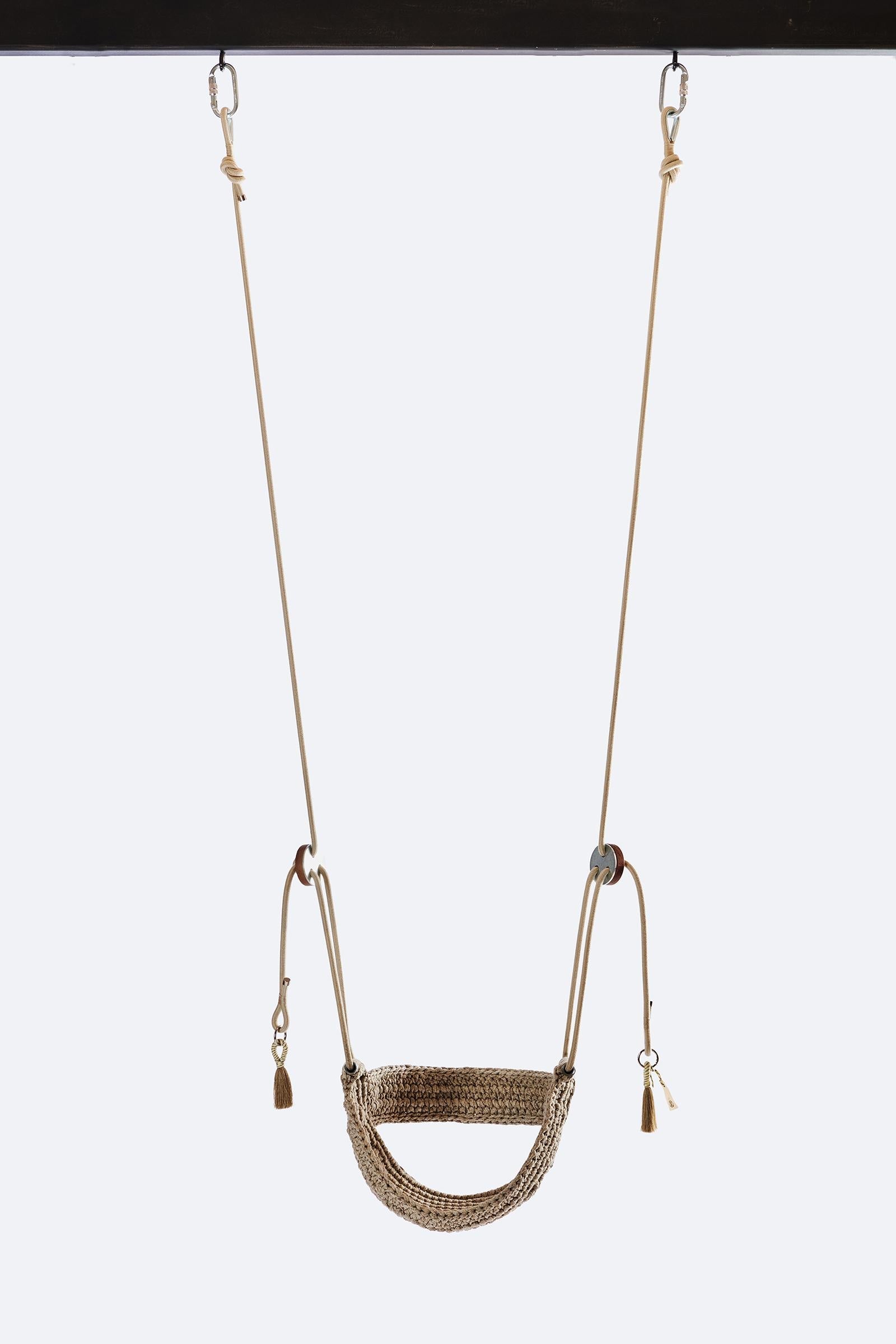 Brown woven swing hanging against a white background