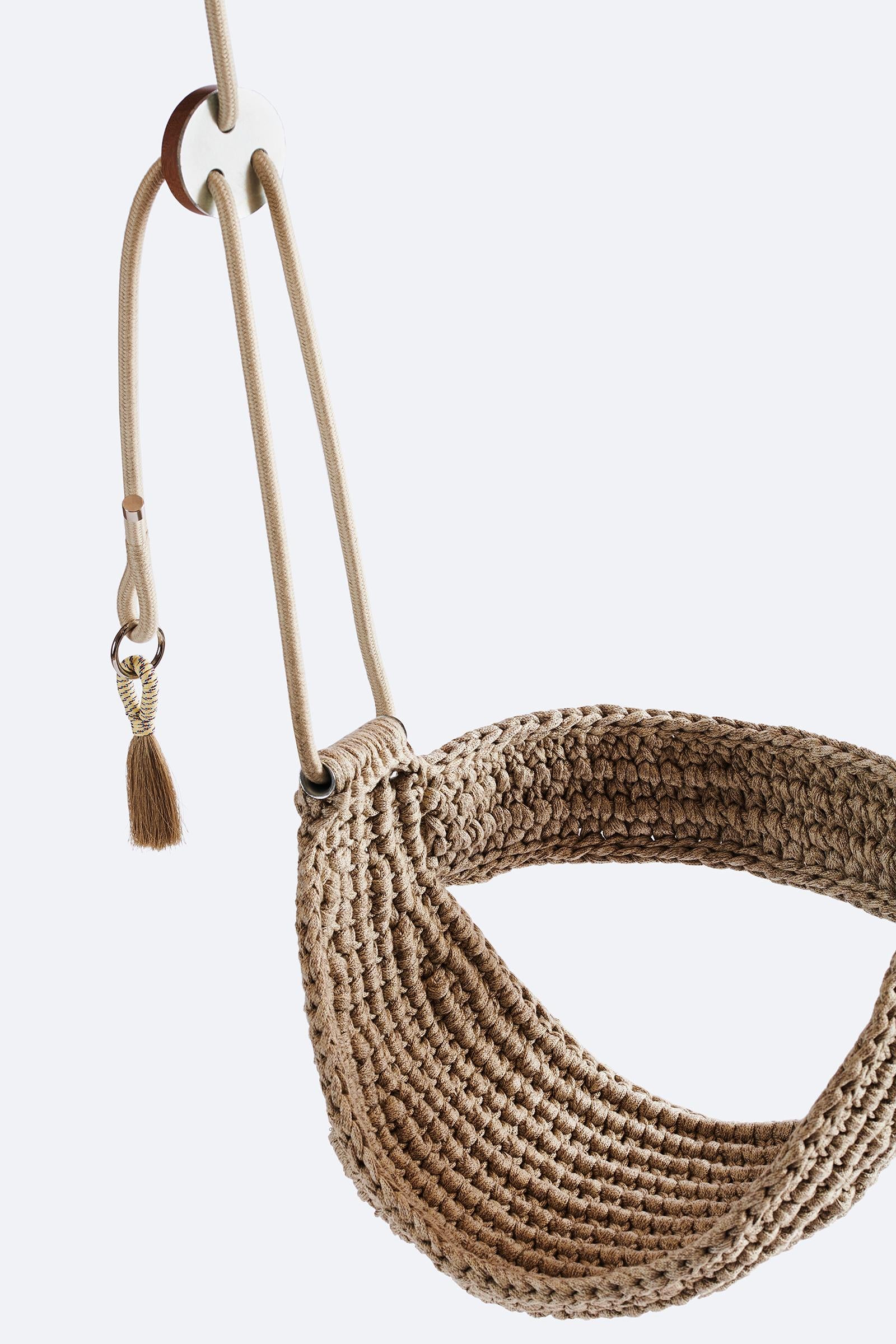 Brown woven swing with a tassel on a white background