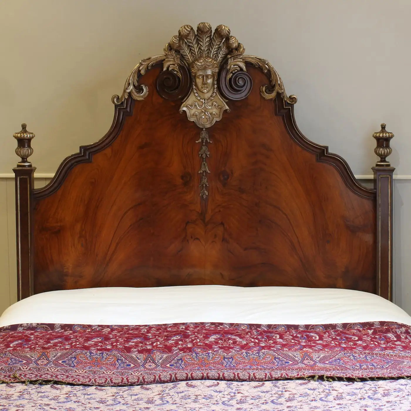 Decorative wooden headboard with intricate carvings on a bed with a patterned blanket.