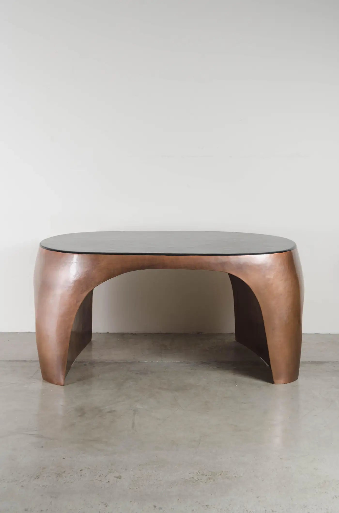 Modern coffee table with wooden base and glass top on a concrete floor.