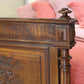 Close-up of a wooden headboard with intricate carvings against a pink textured background.