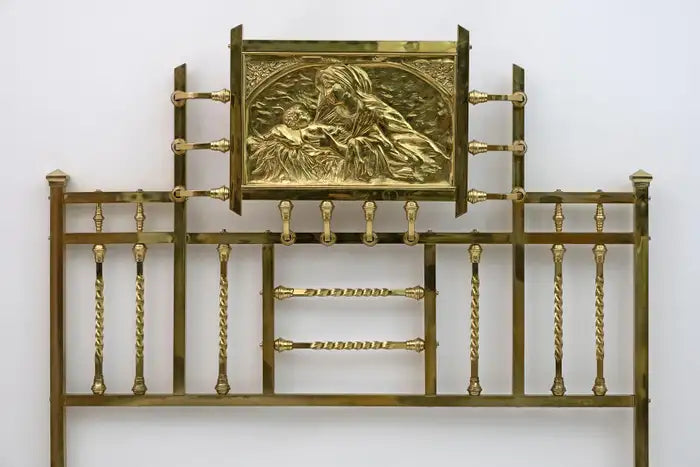 Decorative brass headboard with intricate design on a white background
