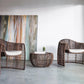 Two wicker chairs with a matching table in a modern room with abstract art on the wall.