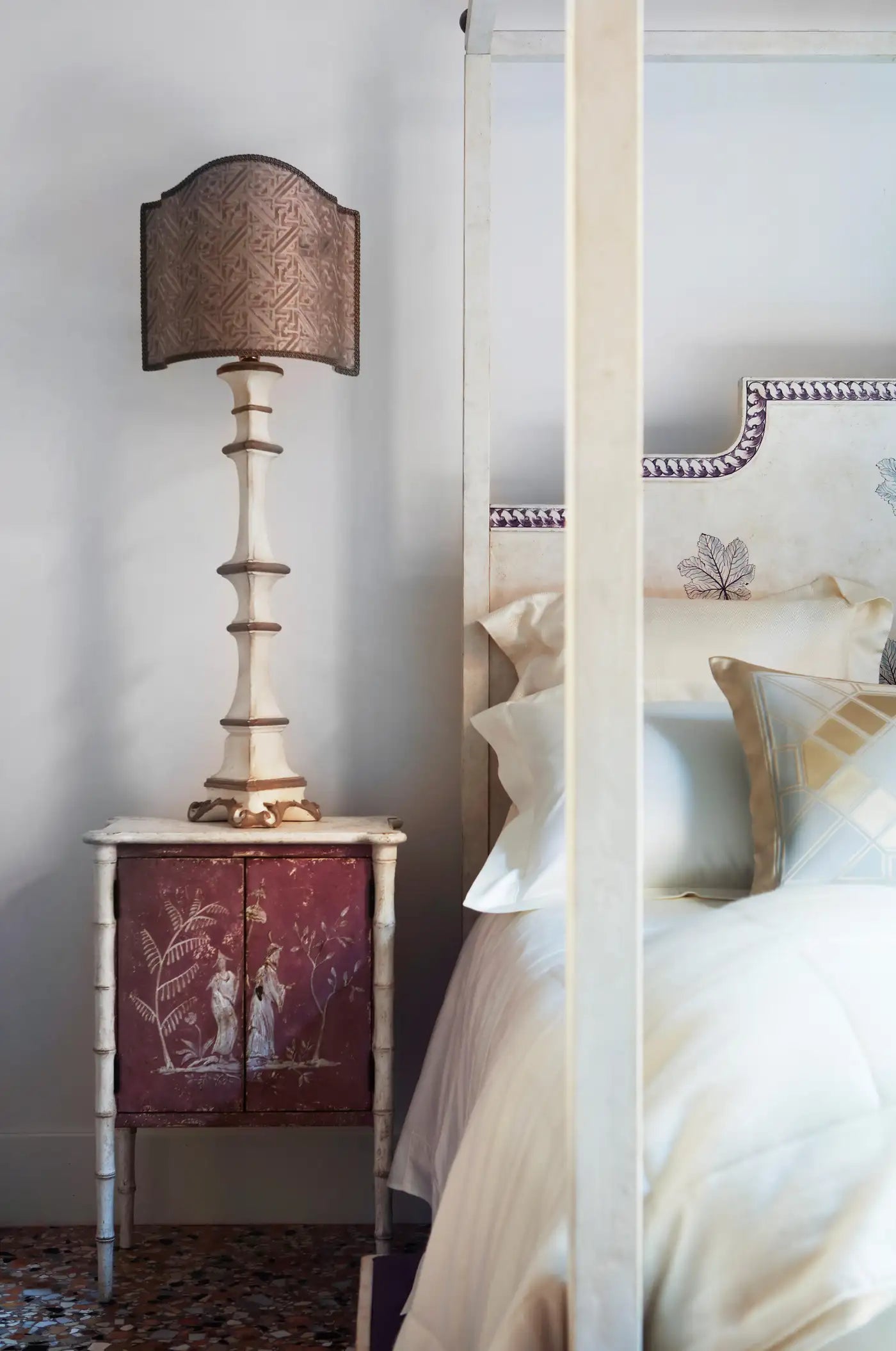 Bedroom with a lamp on a nightstand next to a bed with pillows.