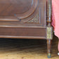 Close-up of an ornate wooden bed with intricate carvings on a wooden floor.