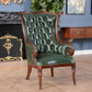 Green leather armchair with wooden frame in a room with decorative elements.